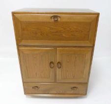 An Ercol blond elm Windsor 469 portable drinks cabinet, having fall-front compartment over twin