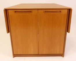 A 1970s Meredew teak freestanding bar, of tapering form, having twin cupboard door, open rear