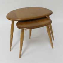 A 1960s Ercol blond elm 'Pebble' nest of two occasional tables, raised on plain turned tapering