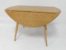 A 1960s Ercol blond elm Windsor 384 dropflap kitchen table, having opposing fall leaves, raised on