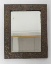 An Arts & Crafts floral embossed copper framed rectangular bevelled wall mirror, the frame with