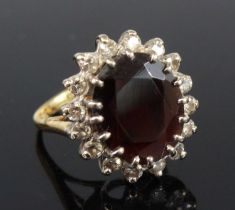 A yellow and white metal, garnet and diamond oval cluster ring, featuring a centre almandine