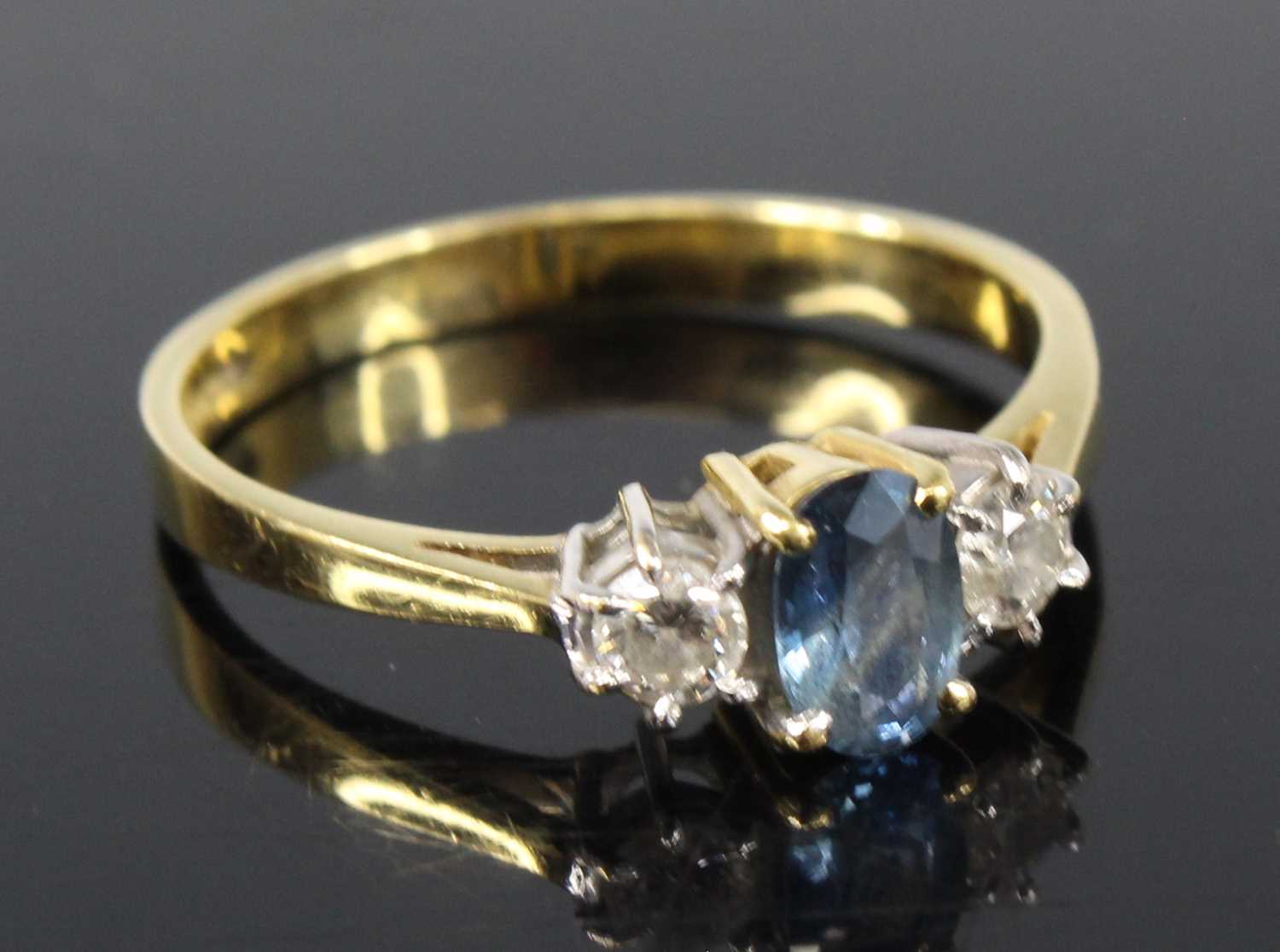An 18ct yellow and white gold, sapphire and diamond three-stone ring, featuring a centre oval