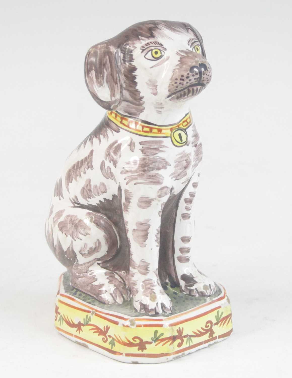 A Delft or Faience polychrome model of a dog, shown seated upon a canted plinth, PAK monogram to the