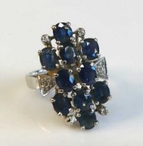 A white metal sapphire and diamond abstract cluster ring comprising 10 oval facetted sapphires in