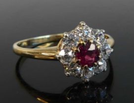 A yellow and white metal ruby and diamond circular cluster ring comprising a centre ruby within a