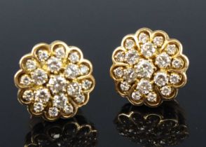 A pair of yellow metal and diamond set flower head cluster ear studs each arranged as 19 graduated