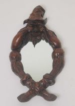 A 19th century continental carved fruitwood wall mirror, the oval plate within a figural surround of