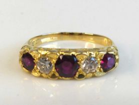 A yellow metal ruby and diamond half hoop eternity ring featuring 3 graduated round rubies