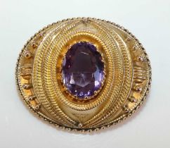 A yellow metal amethyst oval target brooch featuring a 16.8 x 12.7mm oval amethyst claw set within a