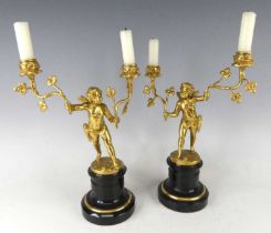 A pair of French circa 1900 gilt bronze figural candelabra, each modelled as a standing winged putti