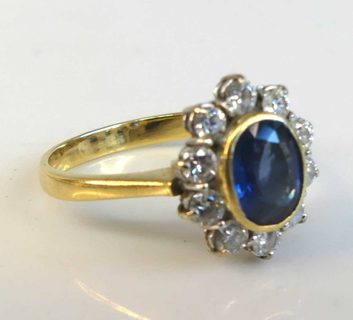 An 18ct yellow and white gold sapphire and diamond oval cluster ring comprising a centre sapphire