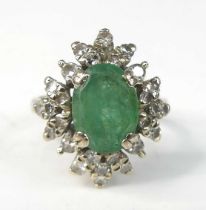 A white metal, emerald and diamond oval cluster ring, comprising a centre oval emerald within a