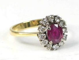 An 18ct yellow and white gold, ruby and diamond oval cluster ring, featuring a centre ruby within