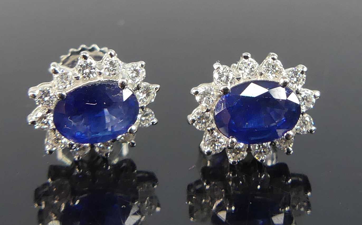 A pair of white metal sapphire and diamond oval cluster earrings, each comprising an oval sapphire
