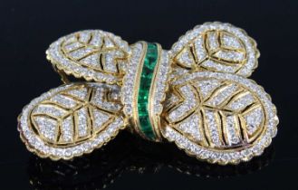 A yellow metal diamond and emerald stylised bow brooch, comprising 203 1.15mm melee cut diamonds