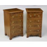 A pair of walnut and figured walnut four drawer bedside chests, each having and feather banded