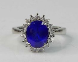 A platinum tanzanite and diamond oval cluster ring, featuring an oval tanzanite within a border of