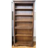 A late 20th Century Old Charm carved oak open bookcase, having a fixed central shelf and four