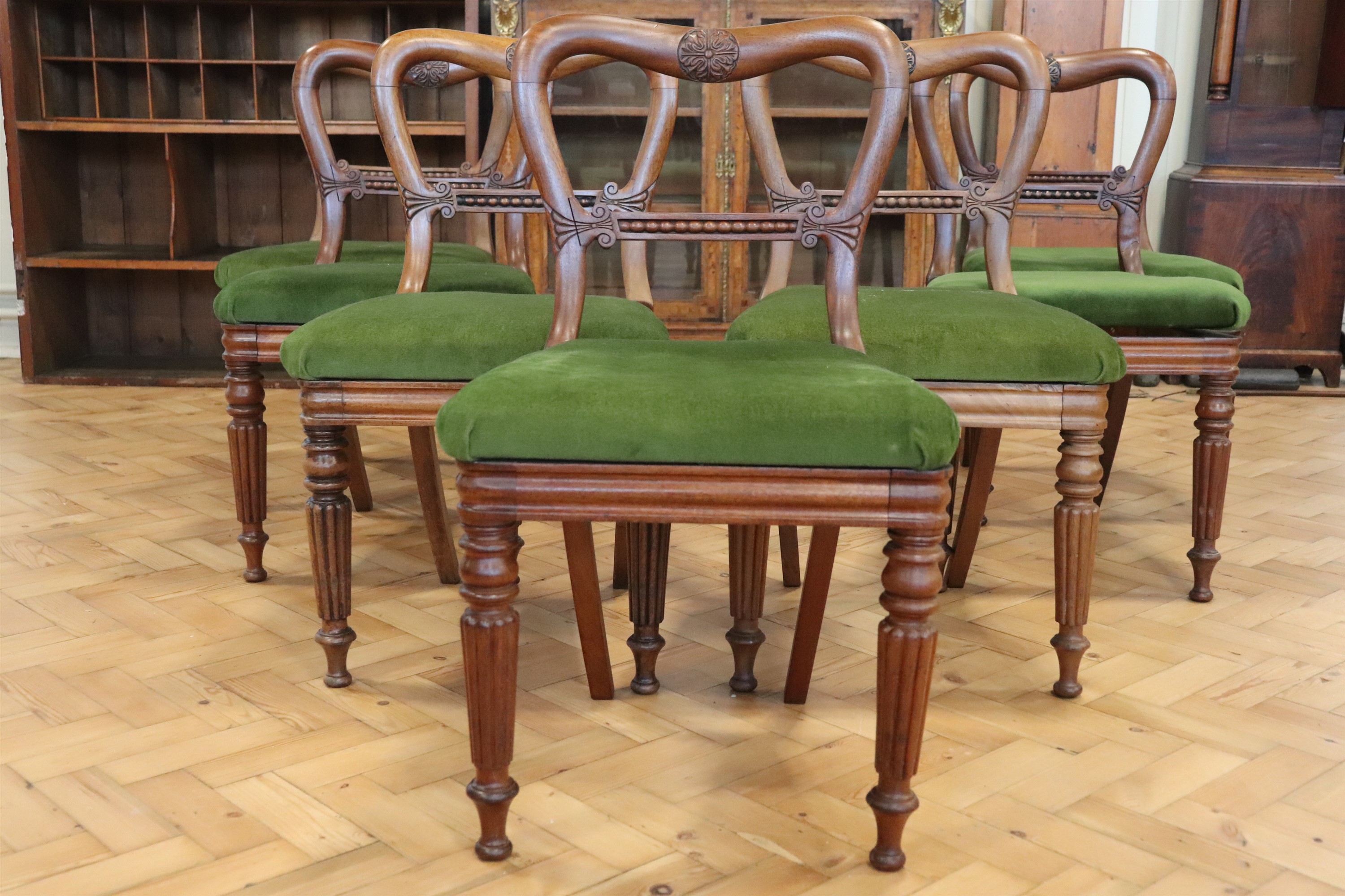 A set of seven Regency mahogany spoon back dining stand chairs, having Gillows style reeded legs and