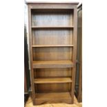 A late 20th Century Old Charm carved oak open bookcase, having a fixed central shelf and three