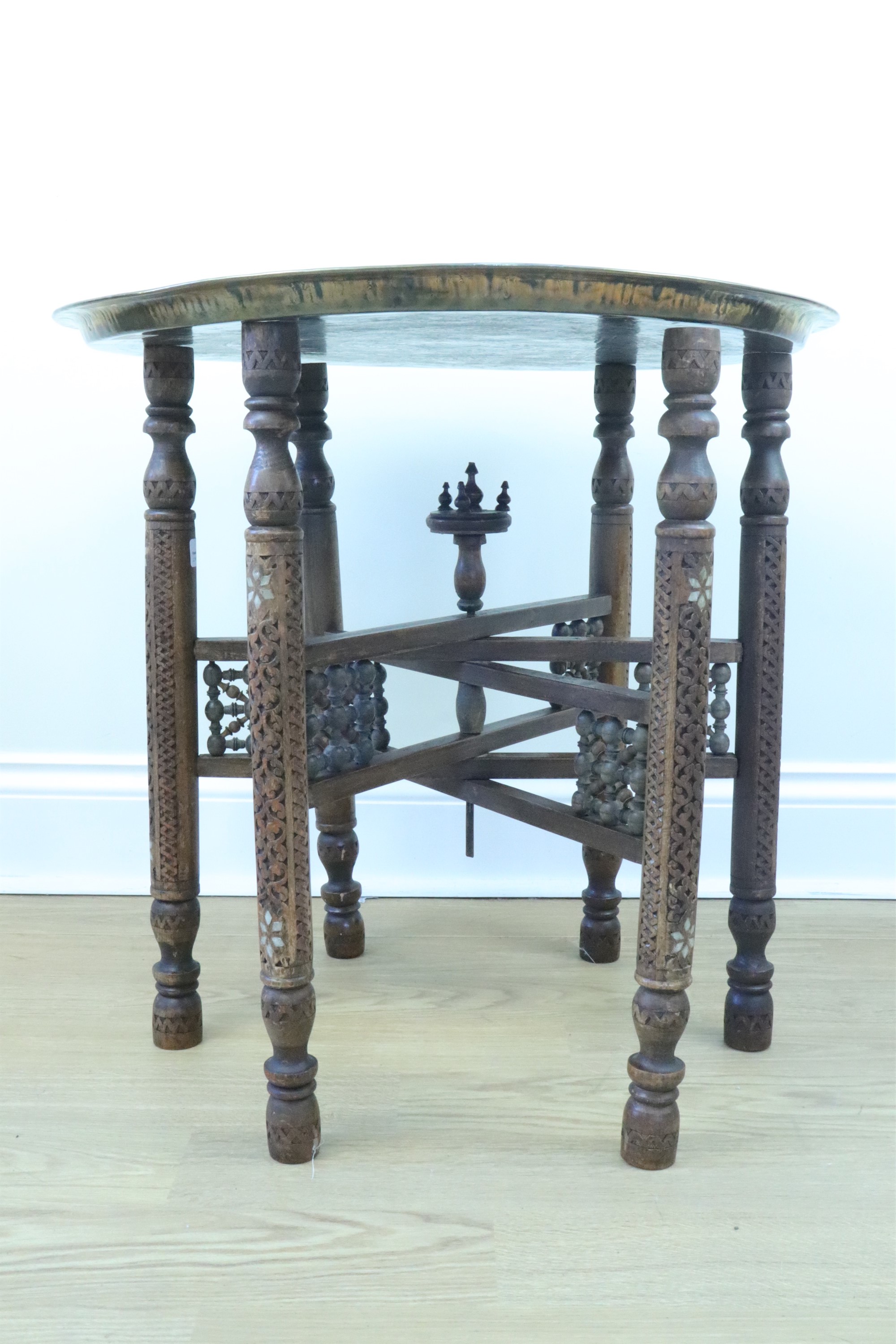 An early 20th Century Middle Eastern brass topped mother of pearl inlaid and carved folding table,