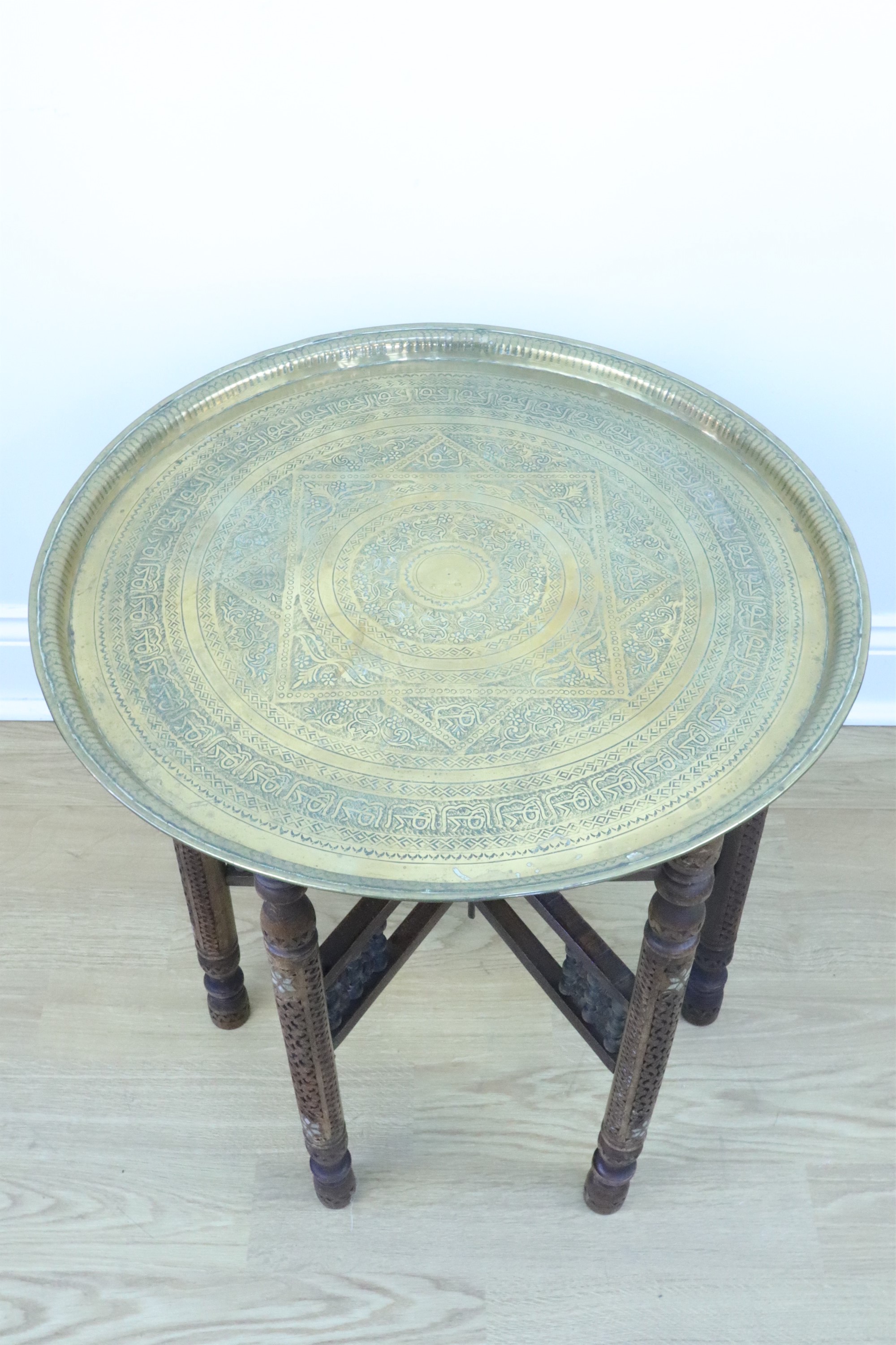 An early 20th Century Middle Eastern brass topped mother of pearl inlaid and carved folding table, - Image 2 of 3