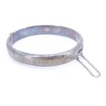 A mid 20th Century silver bangle, having bright cut engraved decoration and hinged with a box catch,