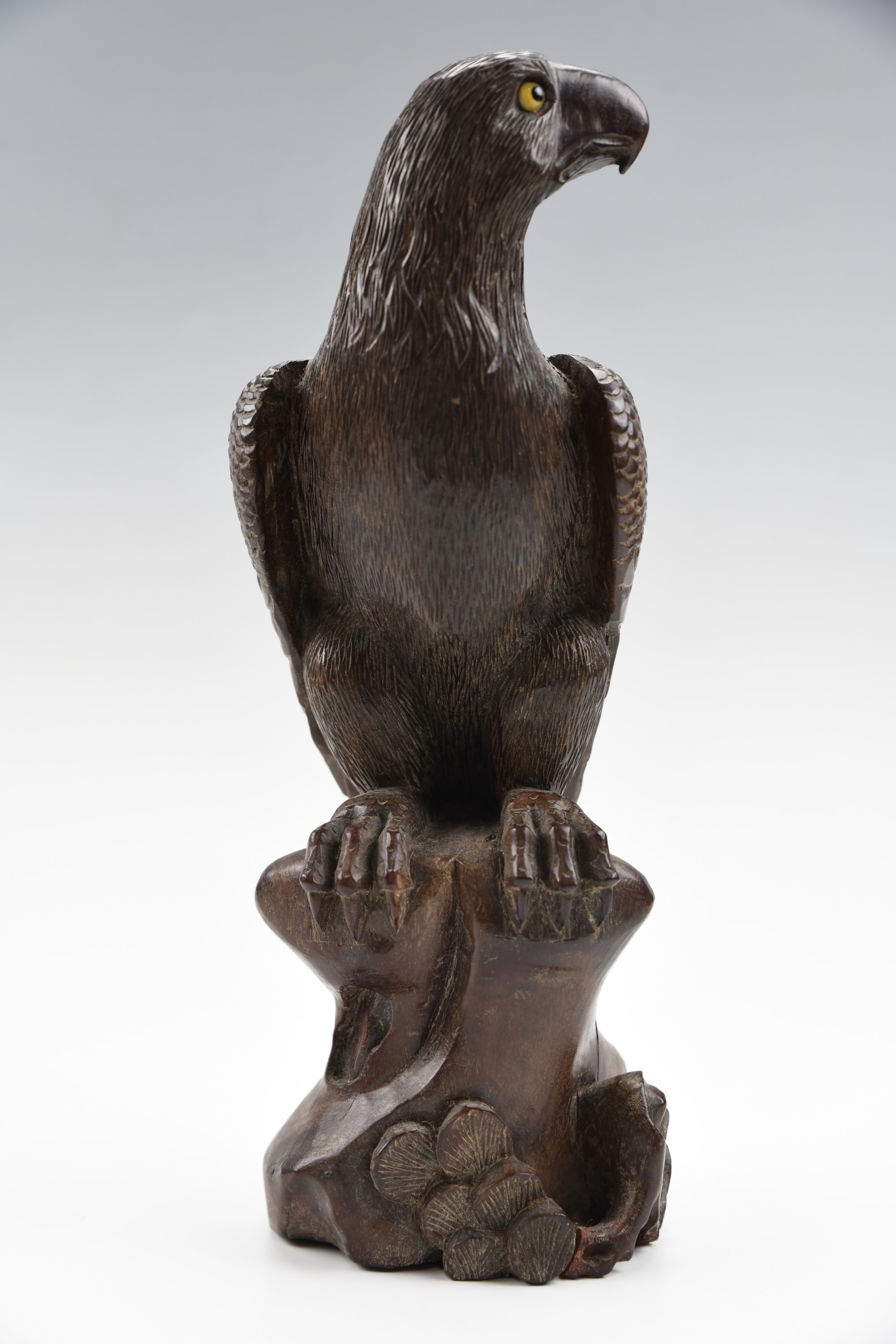 A Japanese carved wooden figure of a perched eagle, having glass eyes, late 19th / early 20th