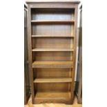 A late 20th Century Old Charm carved oak open bookcase, having a fixed central shelf and four