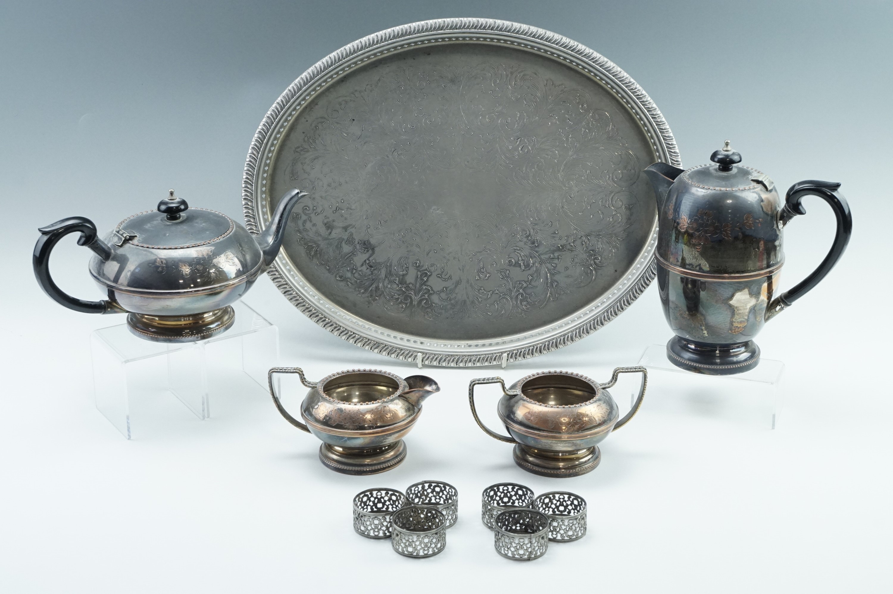 A four-piece electroplate tea set together with a tray and six napkin rings