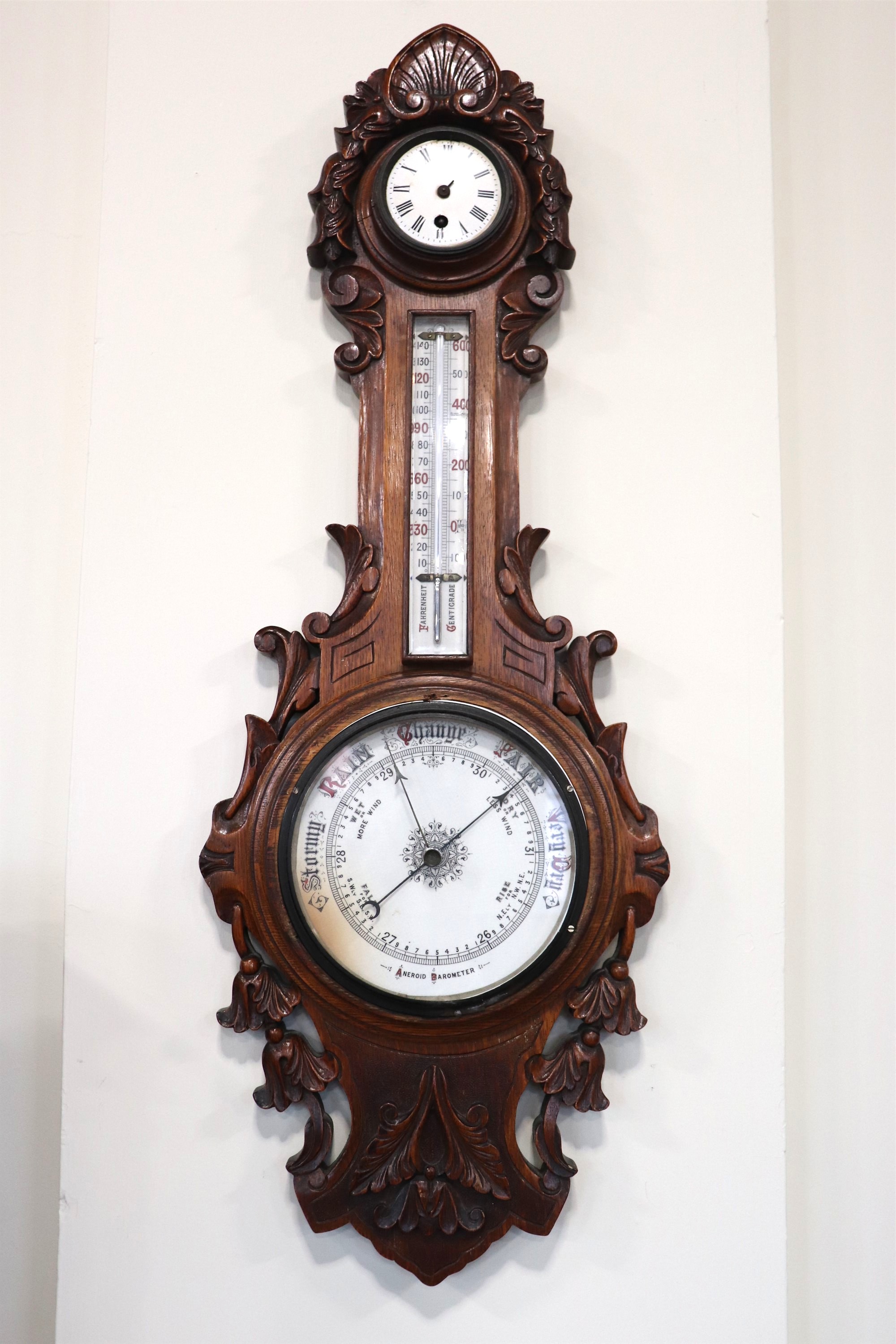 A Victorian carved oak banjo barometer / clock, comprising an aneroid barometer and a thermometer,