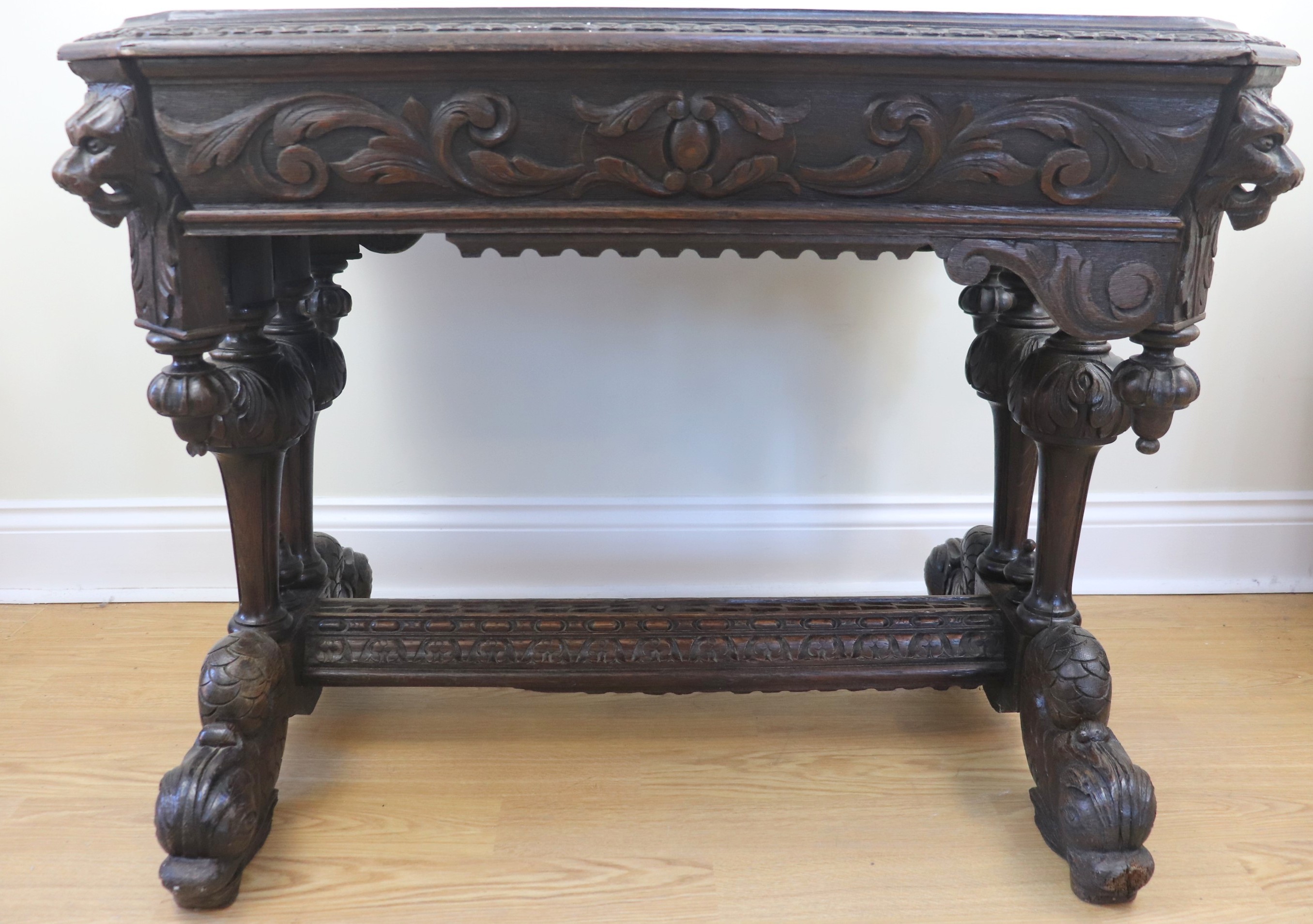 A late 19th / early 20th Century Flemish style heavily carved oak writing table, decorated overall