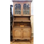 An Art Nouveau tambour fronted oak bureau bookcase with leaded glass doors, tambour key present (