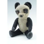 A vintage toy panda Teddy bear, having glass eyes, articulated limbs with leathercloth pads and a
