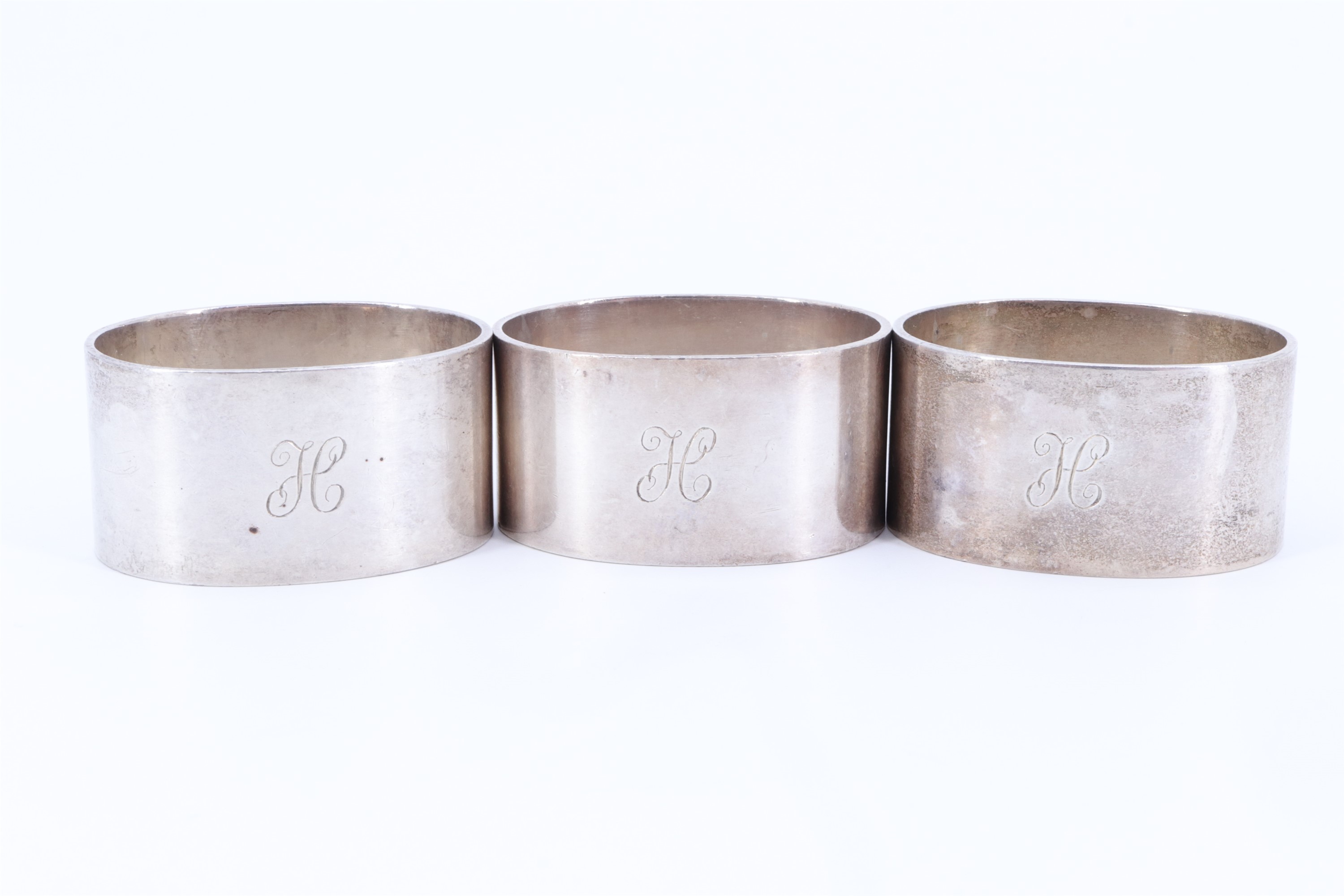 A trio of 1930s heavy silver napkin rings, of oval section and bearing the engraved initial H,