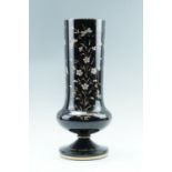 A Victorian black glass vase, of cylindrical form having a compressed ovoid base on a pedestal foot,