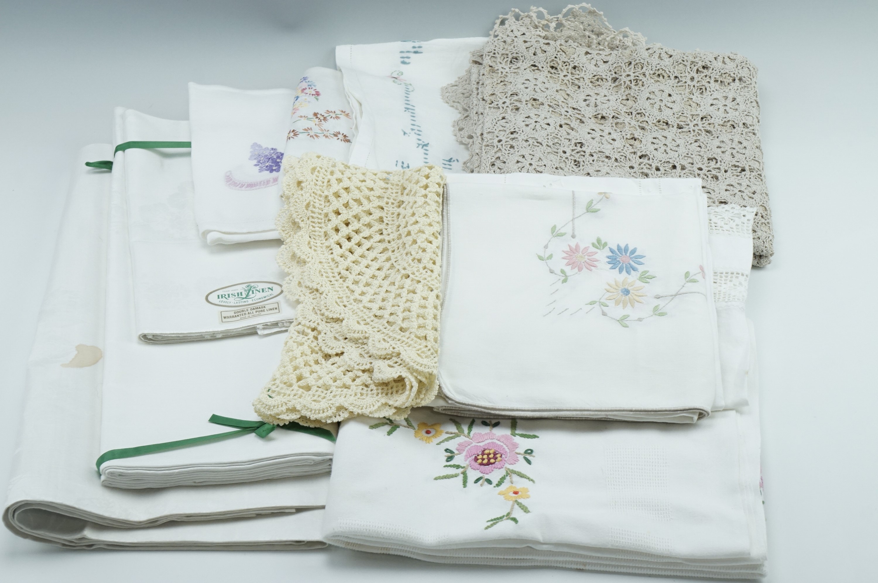 A quantity of vintage embroidered table cloths, crochet work, linen table cloths and napkins