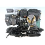 A large group of camera accessories, including light meters, flashes, camera bags, a tripod, etc