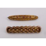 A late 19th Century 15 ct yellow metal navette shaped brooch, set with a line of alternating red