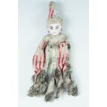 A late 19th Century bisque porcelain headed doll, having glass eyes and wearing a pulcinella style