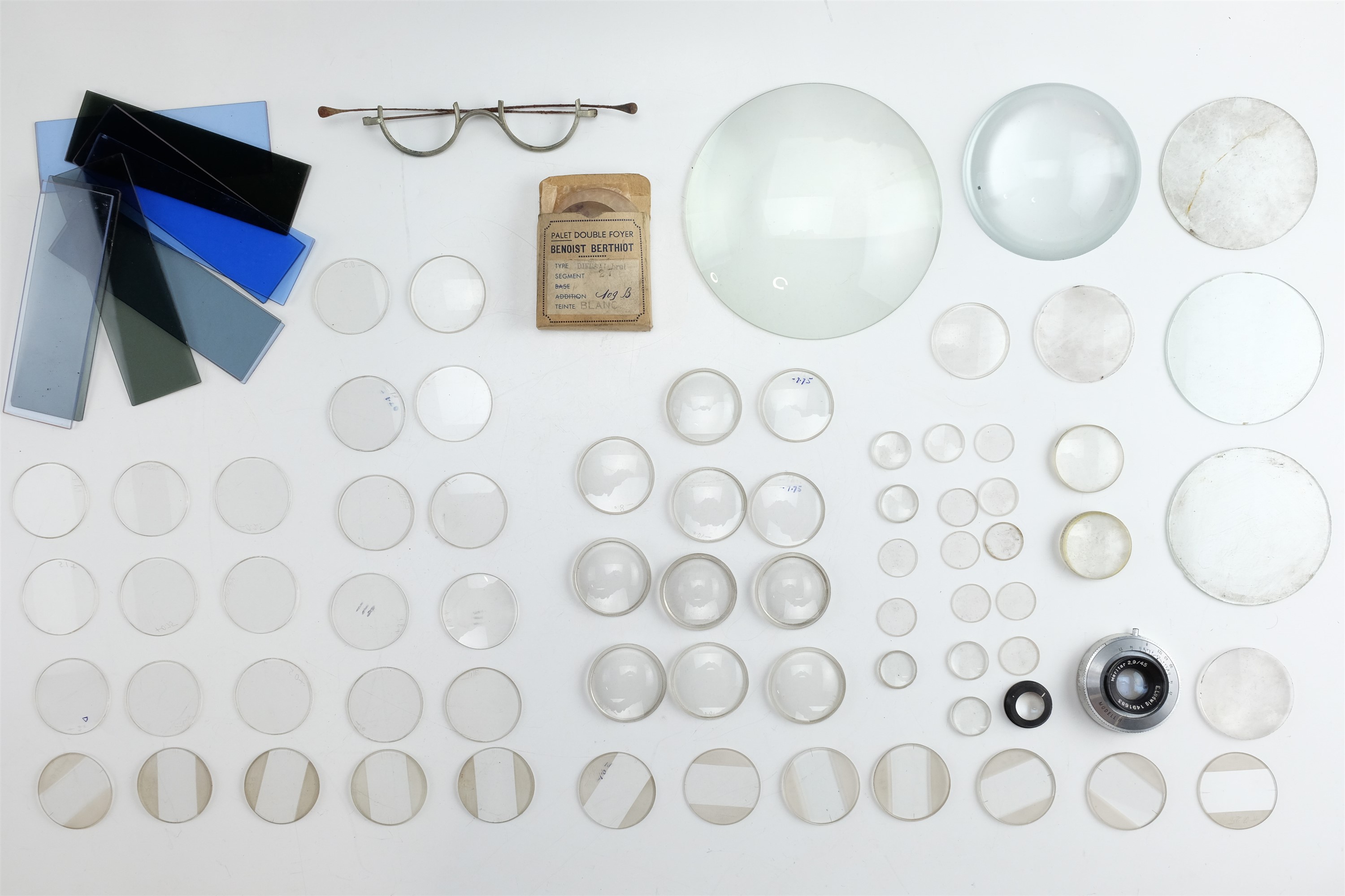 A quantity of 1940s spectacle lens blanks, varying strengths, together with coloured filters,