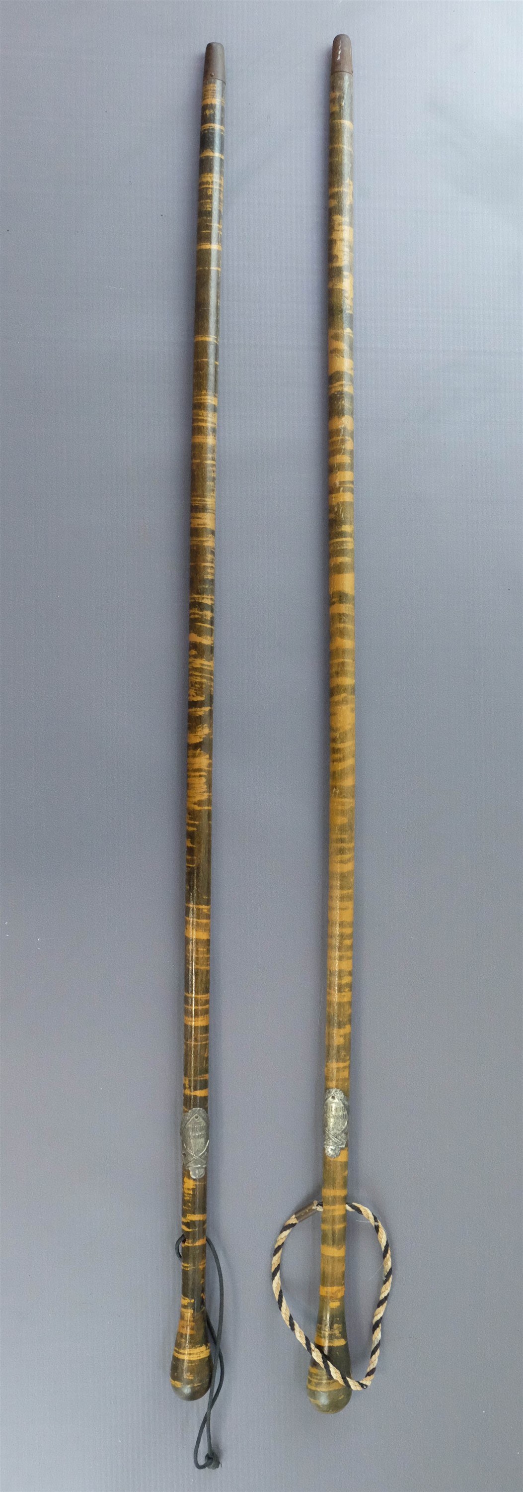 Two inter-War German walking sticks bearing army reservist plaques and one having a lanyard in