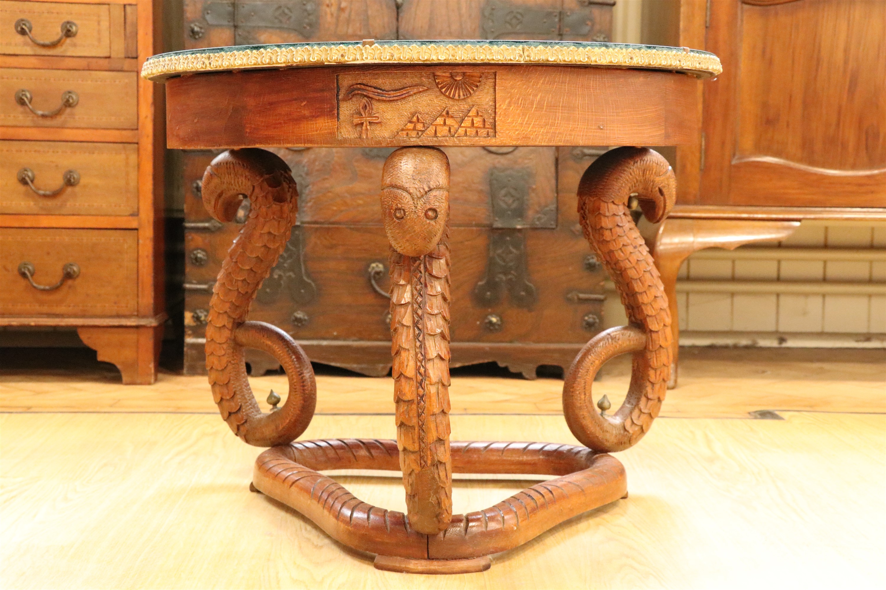 An Egyptian carved hardwood coffee table, having serpent-form legs and a glass and peacock feather - Image 4 of 4