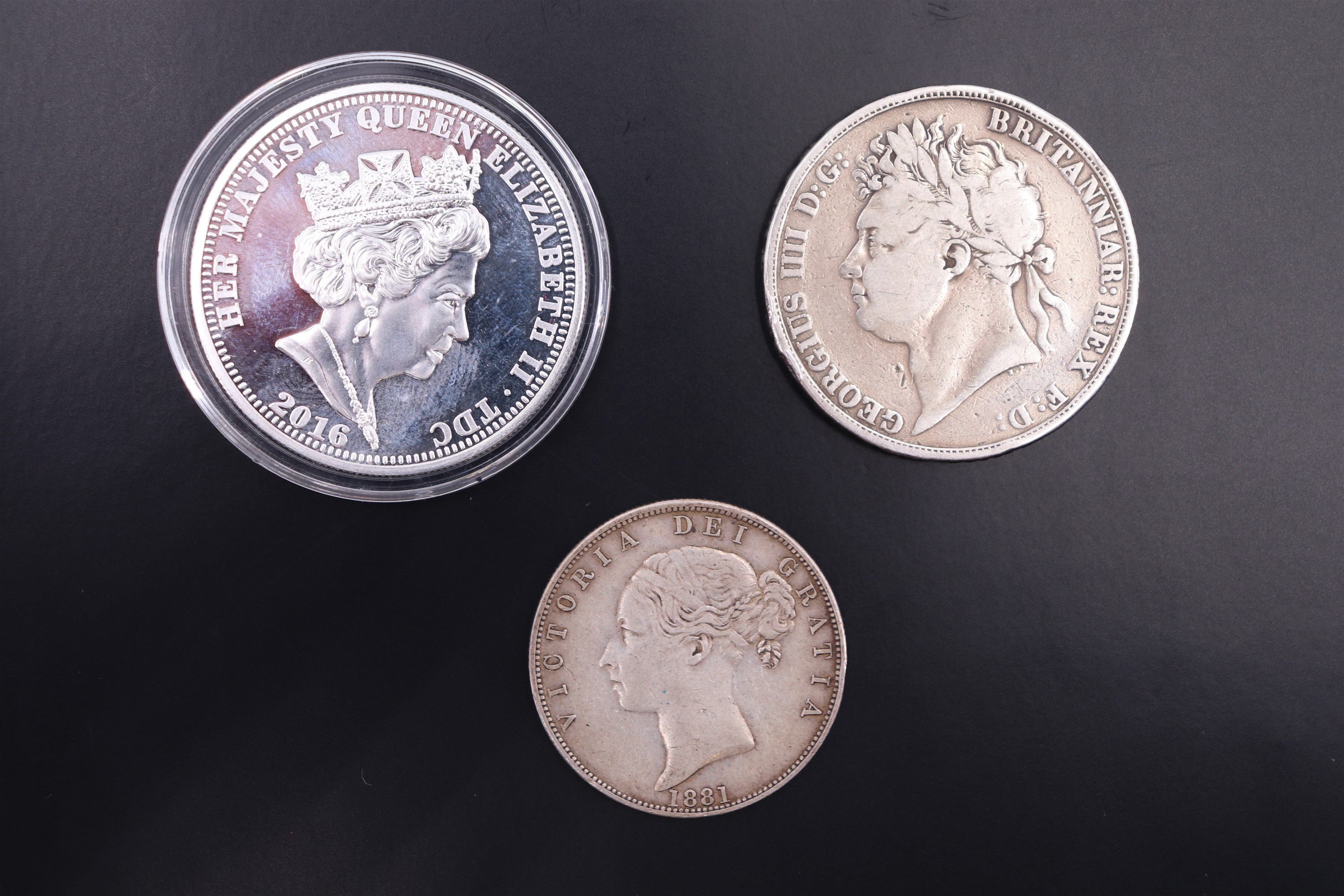 A George IV 1821 silver crown coin, an 1881 half crown and a 2016 silver £5 coin