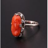 A relief-carved coral finger ring, depicting a female profile bust, set on a 9 ct yellow metal