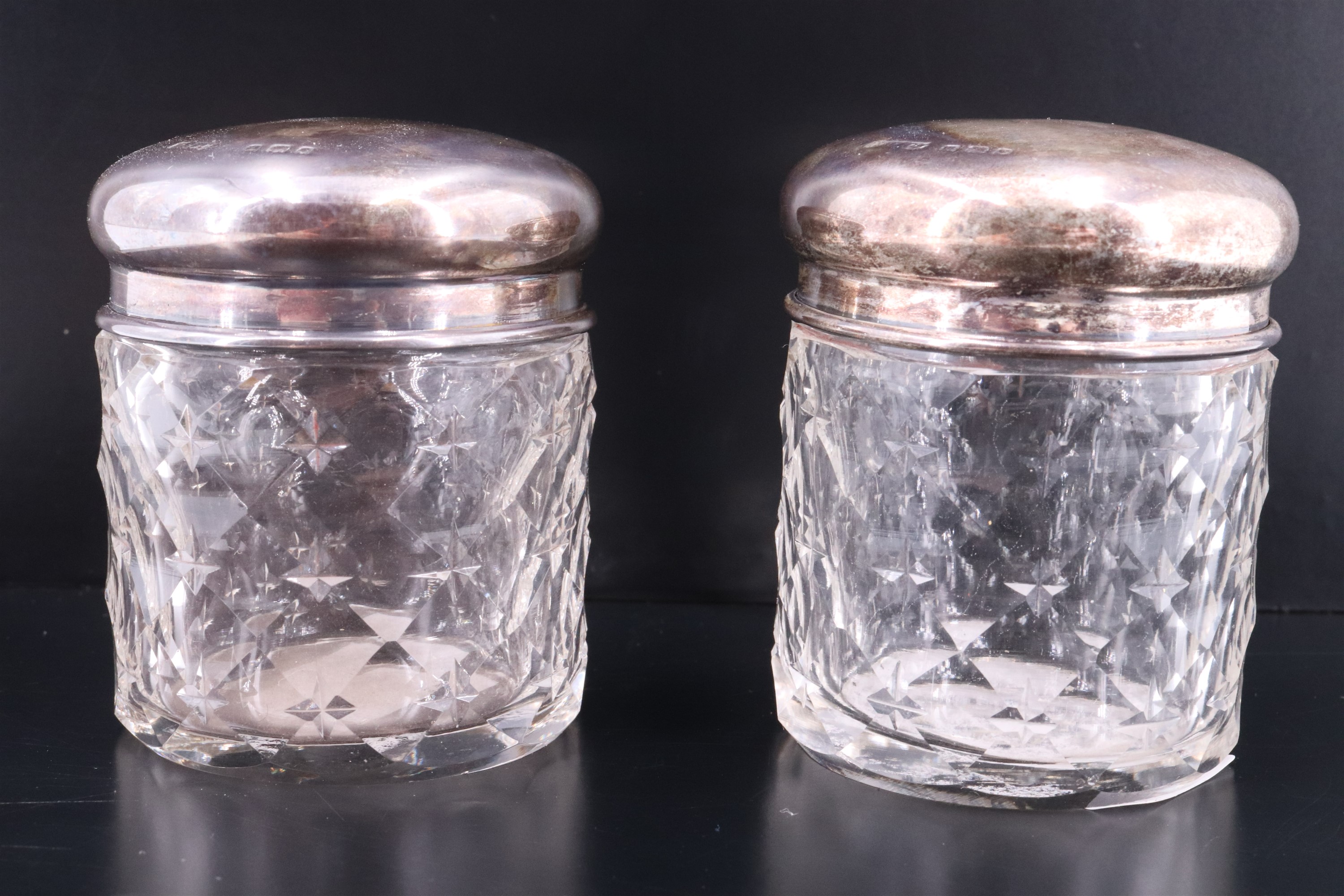 A pair of George V silver topped cut glass dressing table containers, having star and diamond