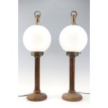 A pair of columnar wooden table lamps having glass globe shades, 61 cm