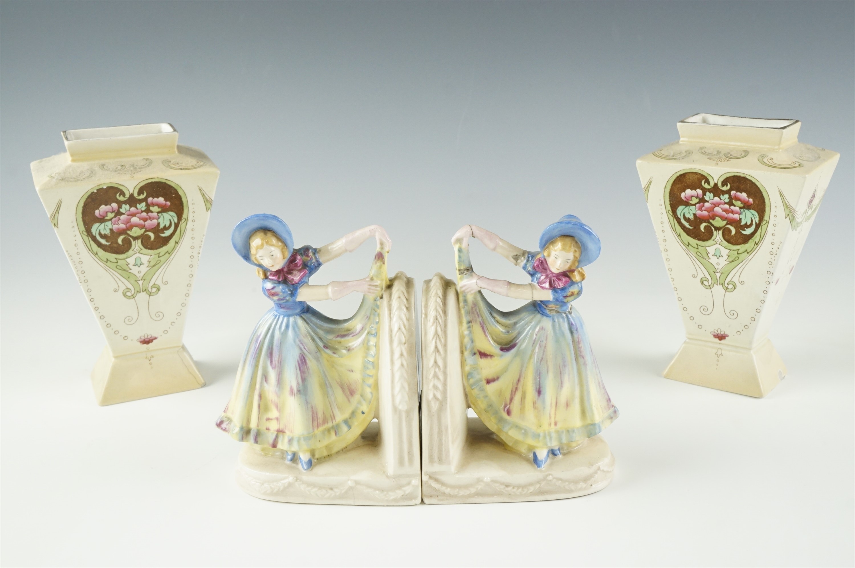 A pair of 1920s figural ceramic book ends, modelled as a girl lifting her hem, marked '37144' to the