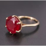 A modern 9 ct gold and ruby dress ring, having a 12 mm brilliant basket set between open tapering